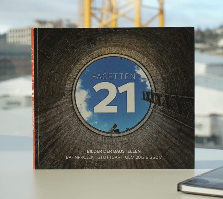 Buch "Facetten 21" hochkant auf weißer Fläche, Umschlag zeigt Blick nach oben durch kreisförmigen Bauschacht.