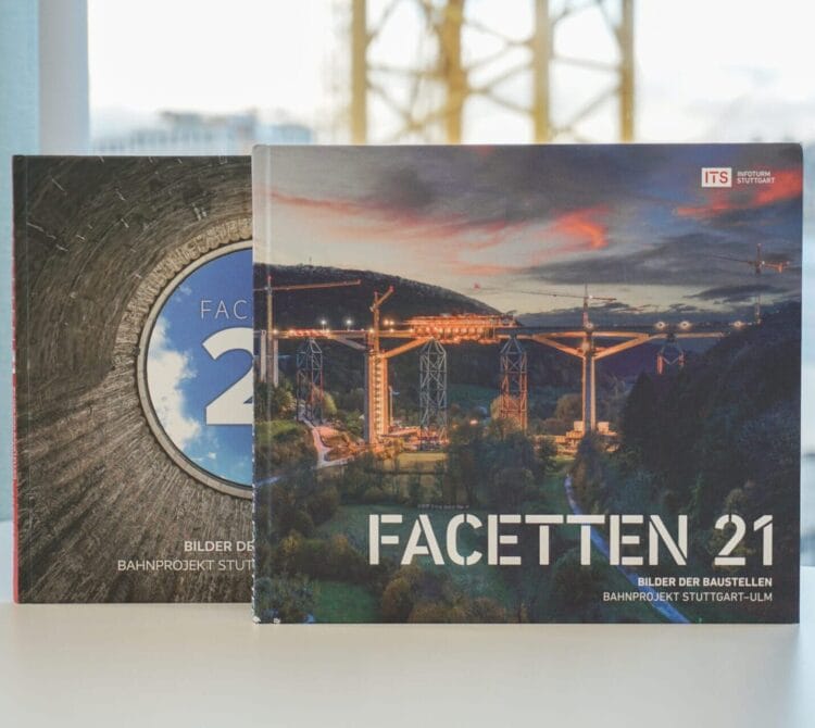 Zwei große Bücher mit den Titeln "FACETTEN 21" und "FA" mit Bauszenen auf den Einbänden auf einem Tisch.