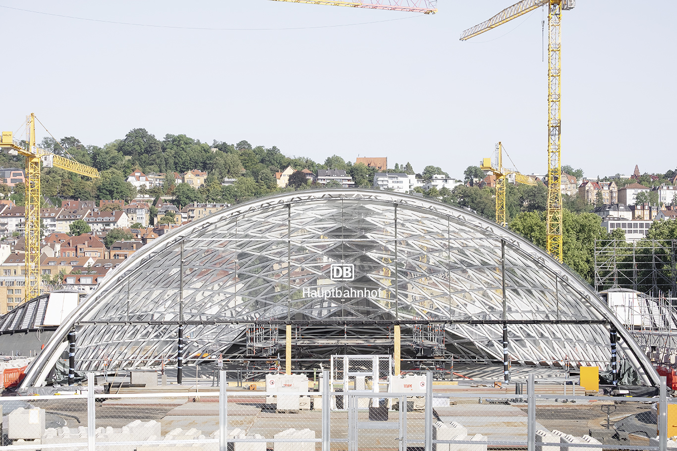Glas- und Stahlkuppel im Bau am Stuttgarter Hauptbahnhof, Kräne im Hintergrund.